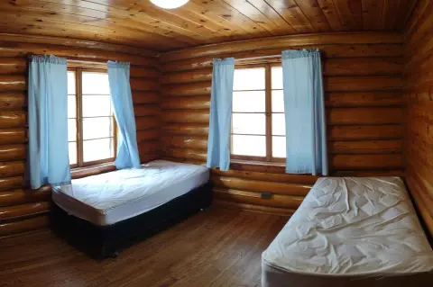 An interior view of a log cabin bedroom with two twin beds.