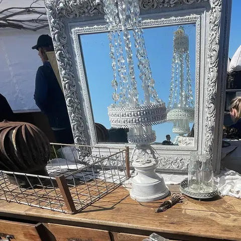A decorative mirror and vintage items displayed on a wooden table at an outdoor market.