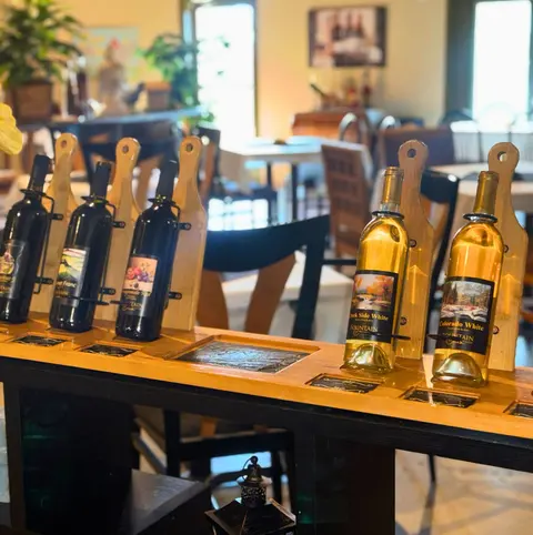 Wine bottles displayed in wooden stands on a table inside a restaurant.