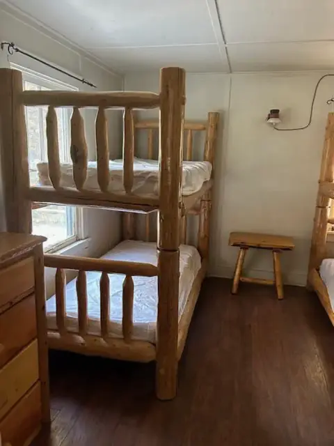 A bedroom with wooden bunk beds and a small stool.