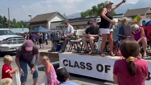 People sit on a parade float outdoors.