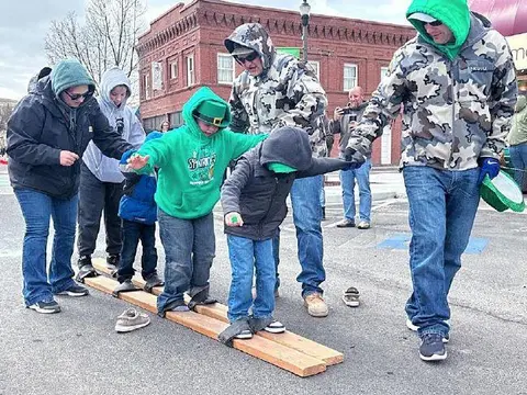 People participate in an outdoor activity walking on wooden boards.