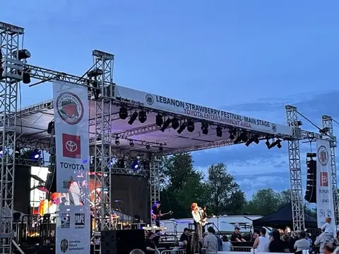 An outdoor concert stage with performers and a crowd.