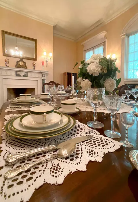 A dining table set with fine china and silverware inside a dining room.