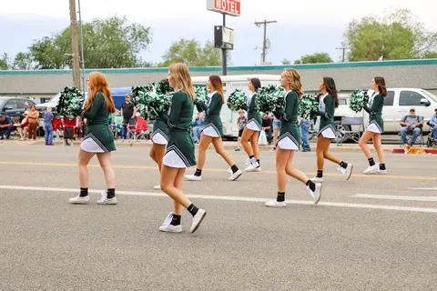 A line of cheerleaders marching in a street parade.