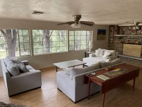 A living room with couches, a coffee table, and large windows looking outside.