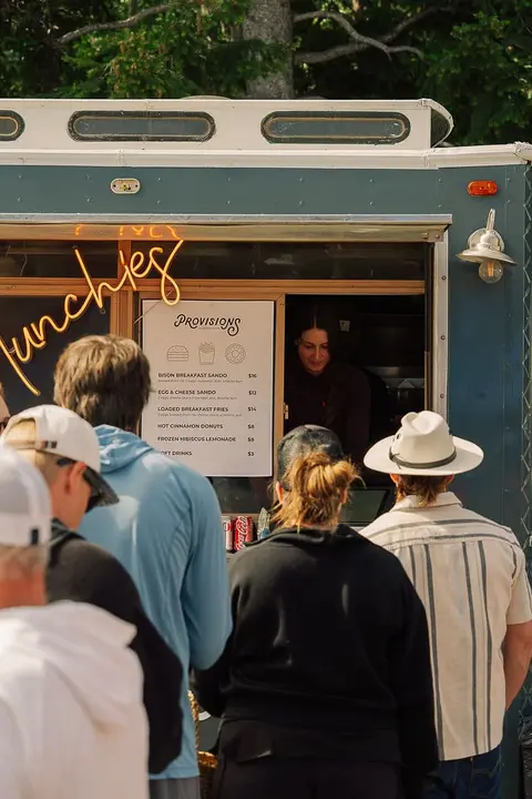 A line of people stands outside a food truck to order.