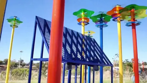 A colorful playground structure stands against a clear blue sky.