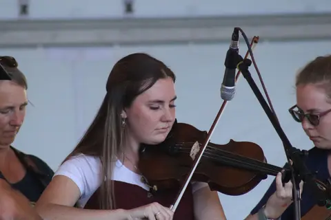 A woman plays the violin while performing with a group.
