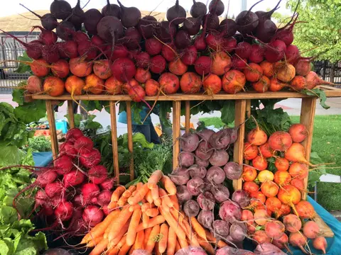 A display of fresh root vegetables including beets and carrots at a market.