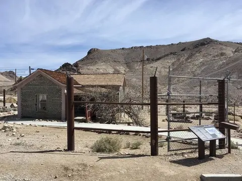 An exterior view of a building made of bottles in a desert landscape.