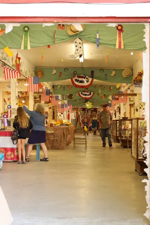 People walking through an indoor hall decorated with patriotic banners and ribbons.
