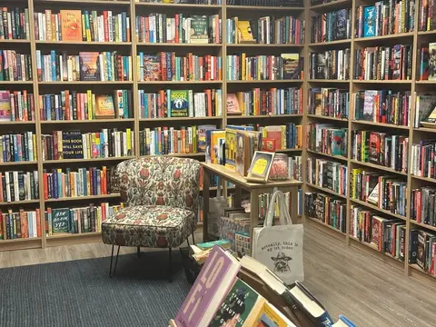 A bookstore interior with shelves filled with books and a patterned armchair.