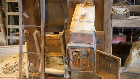 A vintage wall-mounted telephone and a canvas bag resting in a wooden interior space.