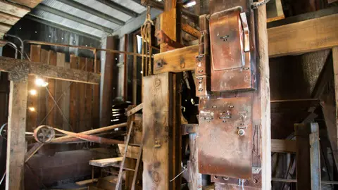 Interior view of an old industrial workspace with wooden structures and vintage electrical boxes.