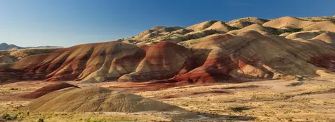 A landscape view of colorful striped hills under a clear blue sky.