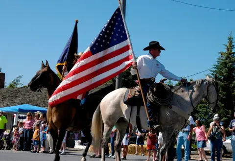 People on horseback carrying flags during an outdoor event.