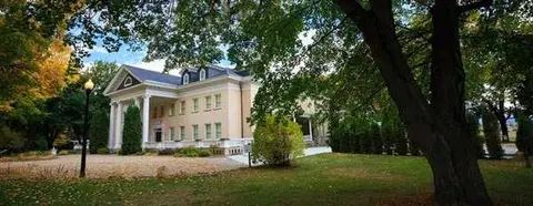 A large historic-style building surrounded by trees and lawn.