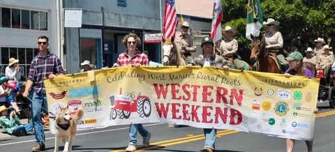 People carry a banner reading Western Weekend in a street parade.