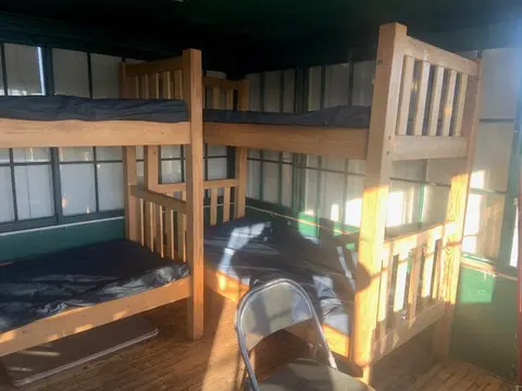 An interior view of a room with wooden bunk beds and a folding chair.