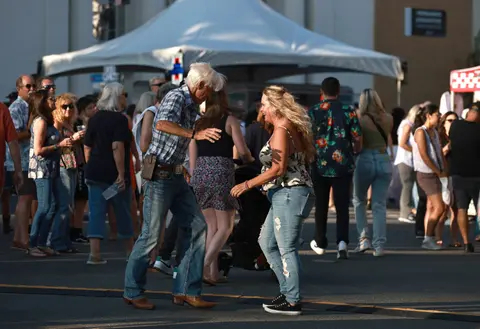 A couple dances outdoors in front of a crowd at an event.