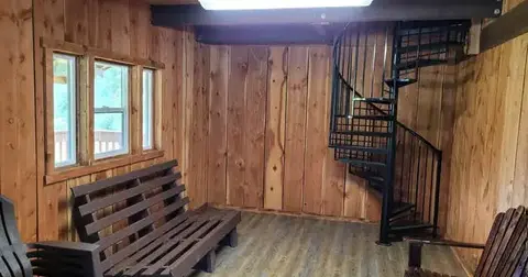 An interior view of a wooden room featuring a spiral staircase and wooden furniture.