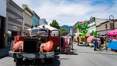 An old truck parked on a street during a community event with people and inflatables.