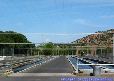 An outdoor facility with long concrete water troughs and overhead wire structures.
