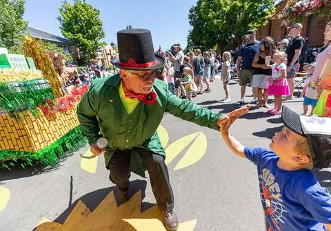 A costumed performer high-fives a young child at an outdoor event.