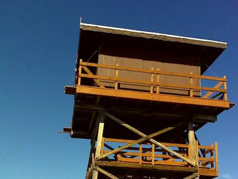 A tall wooden observation tower against a blue sky.