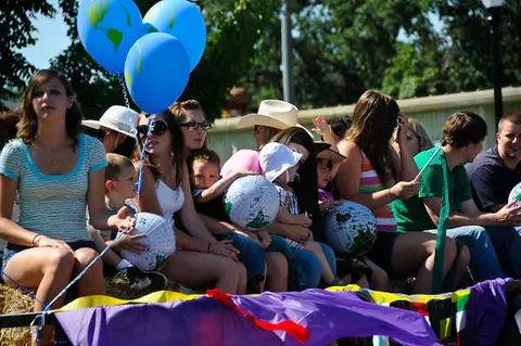 A group of people sitting on hay bales outdoors with balloons and globe decorations.