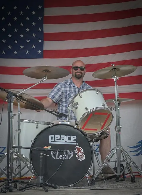 A drummer performs in front of an American flag.