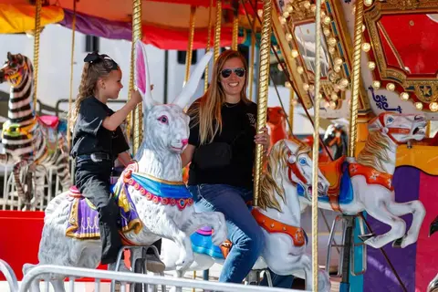 A woman and a young girl ride a carousel.