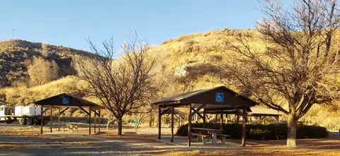 Picnic shelters and tables set among trees in a hilly landscape.