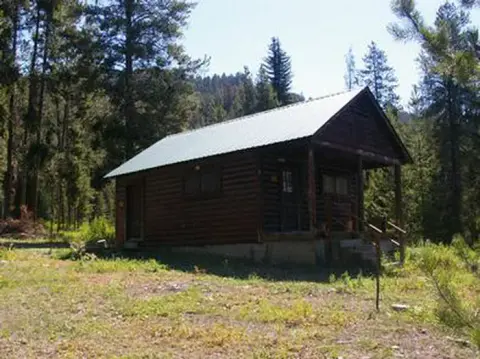 A wooden cabin in a wooded forest area.