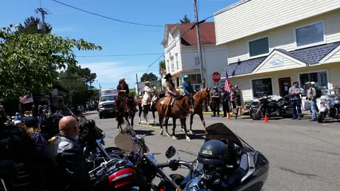 People ride horses down a street during an event.