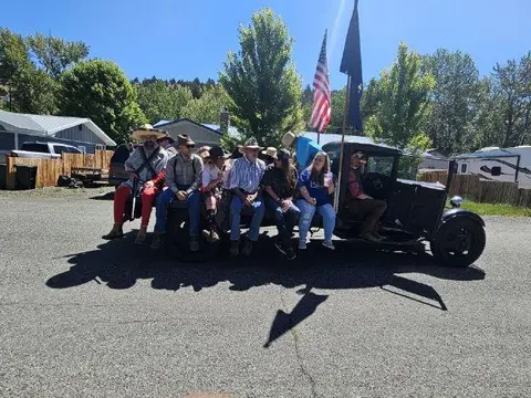 People sit in the back of an old truck outdoors.