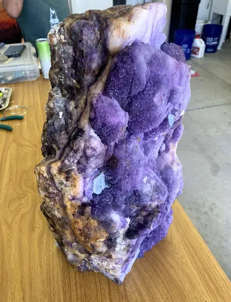 A large purple crystal or mineral specimen sits on a wooden table.