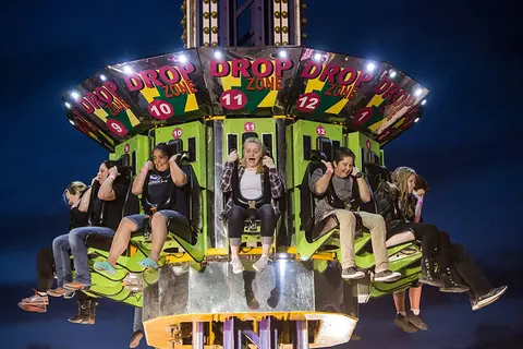 People riding a drop tower amusement ride at night.