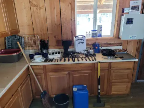 A kitchen counter is cluttered with utensils, dishes, pots, and a coffee maker.