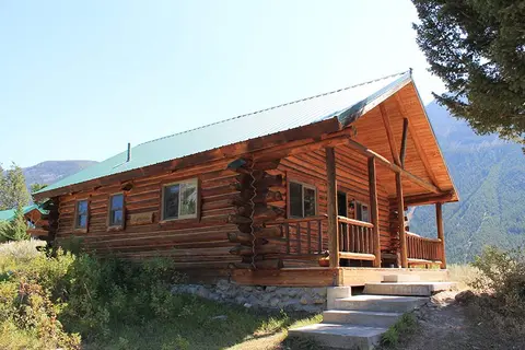 A log cabin sits in a mountainous landscape.