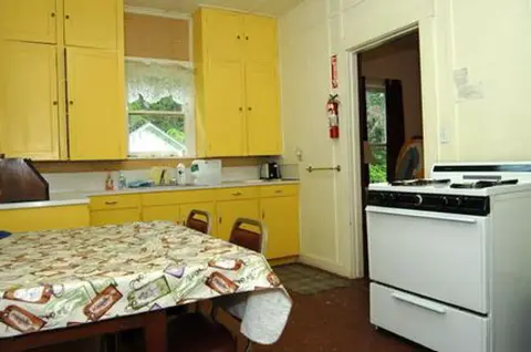 A photo of a retro kitchen with yellow cabinets and a white stove.