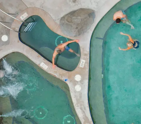 An overhead view of people enjoying a hot spring pool with multiple sections.