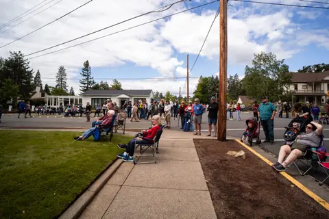 A crowd of people gathers along a street to watch an event.