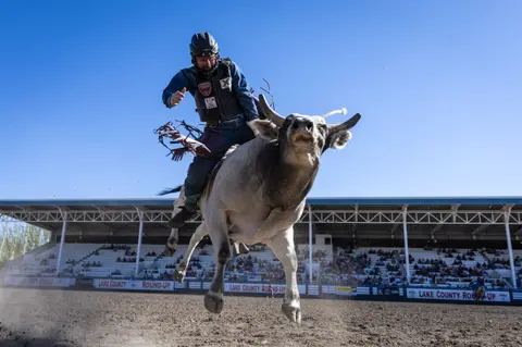 A bull rider riding a bull in an arena.