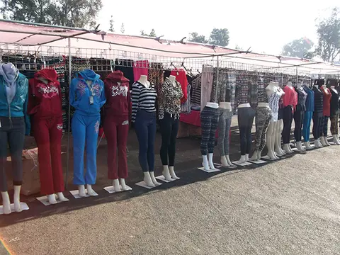 A row of mannequins displaying clothing under outdoor canopies.