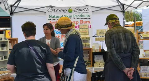 Customers browse natural skin products at a vendor booth.