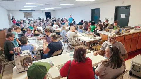 A crowded room with people sitting at tables playing bingo.