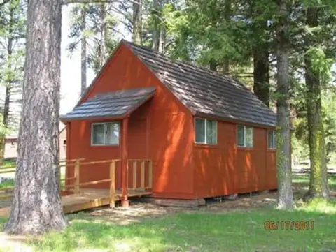A small red cabin nestled among trees in a wooded area.