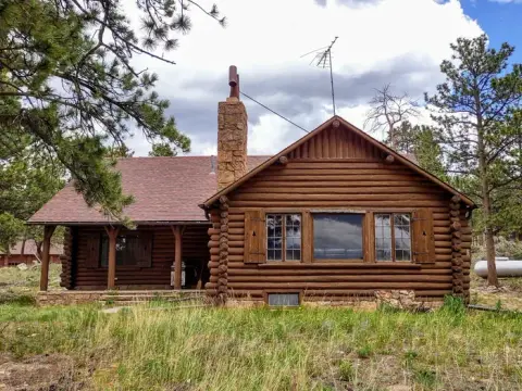 An exterior view of a rustic log cabin surrounded by trees.